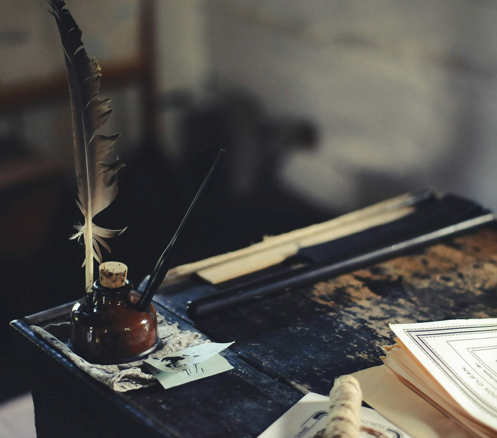 Ink bottle and quill on desk near stack of paper