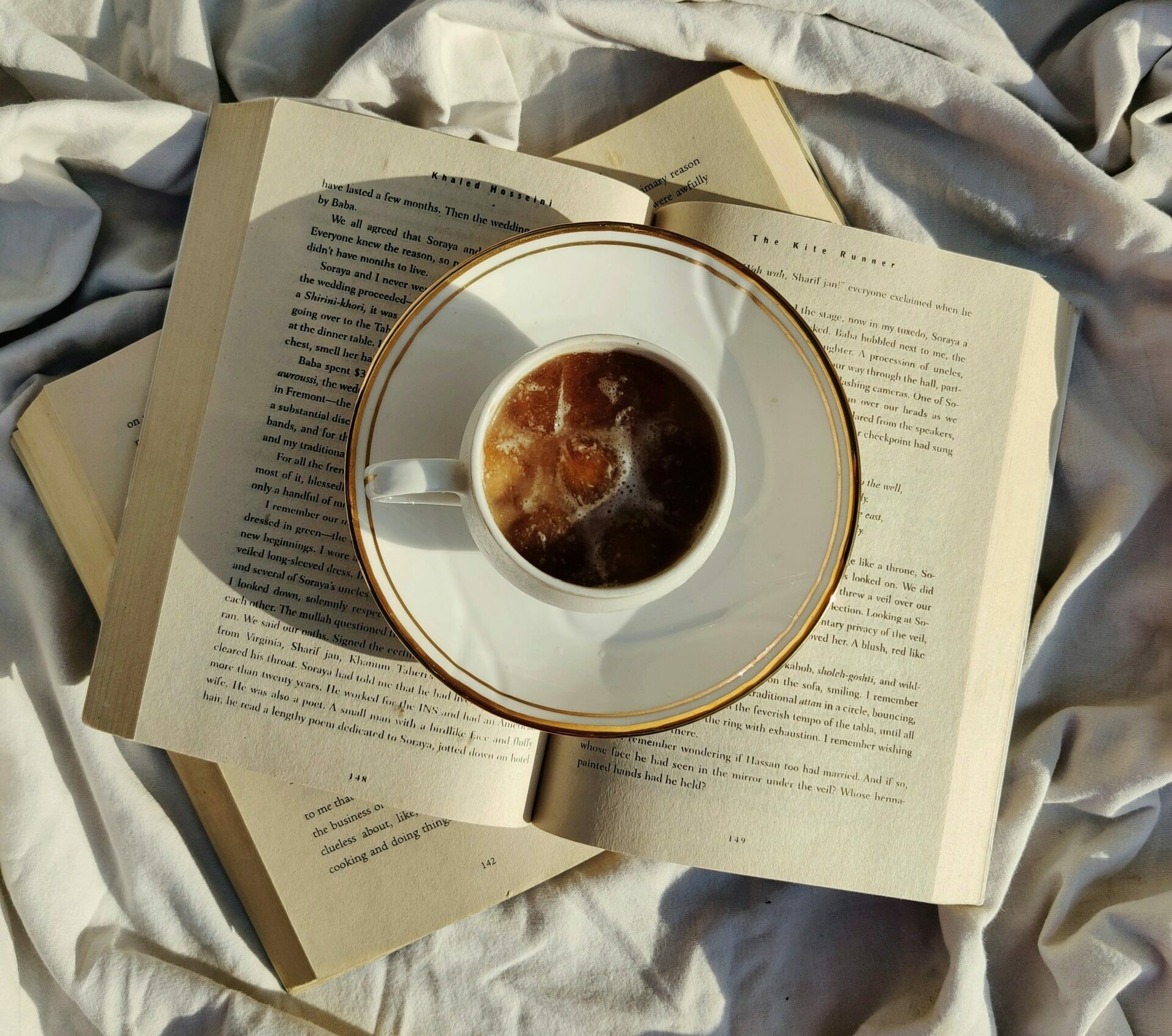 Cup of coffee on open books on white fabric