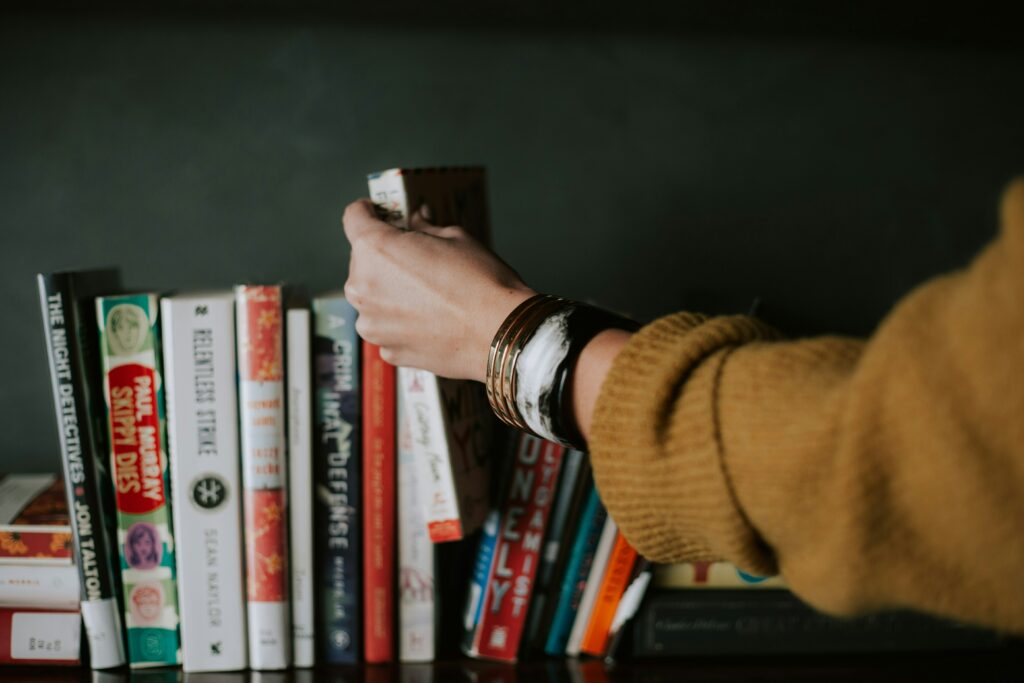 person picking up one book from line of books