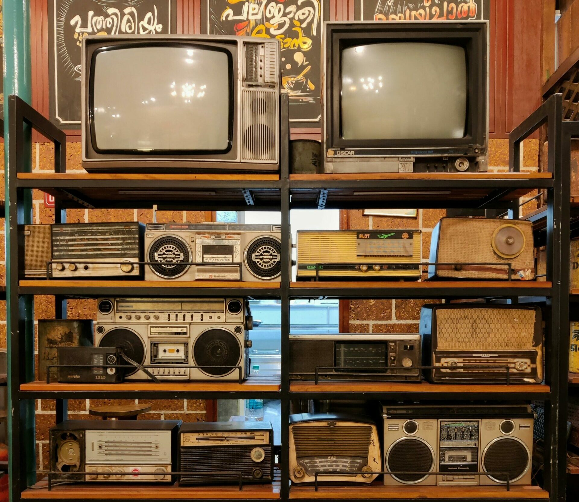 Vintage TVs, radios, boomboxes, and other technology on a shelf