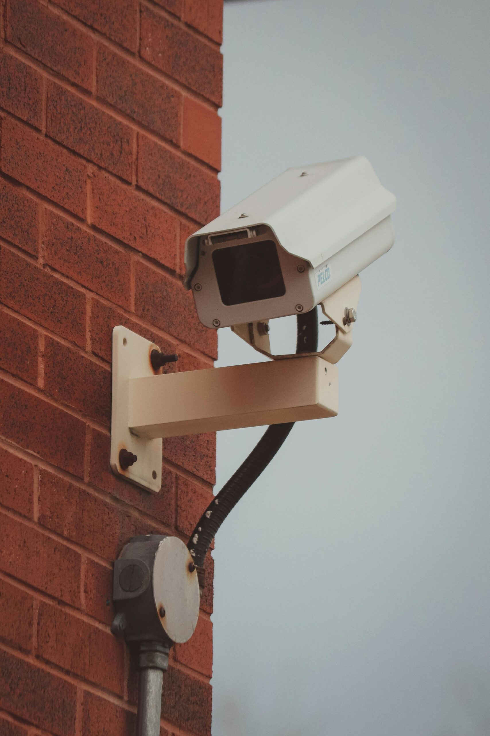 A security camera attached to the side of a brick building